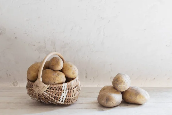 Batatas na cesta no fundo parede velha branca — Fotografia de Stock