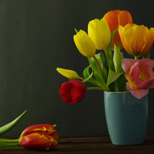 Beautiful tulips in vase on green background — Stock Photo, Image