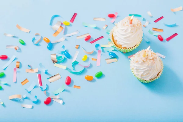Födelsedag hatt med konfetti och cupcake på blått papper bakgrund — Stockfoto