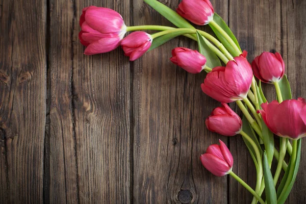 Tulipanes rojos sobre fondo de madera oscura — Foto de Stock