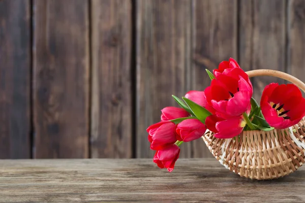 Tulipes rouges dans le panier sur un vieux fond en bois — Photo