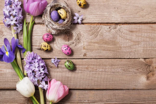 Uova di Pasqua con fiori primaverili su sfondo di legno — Foto Stock