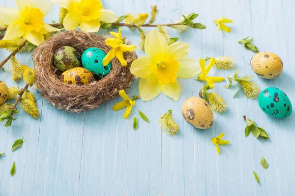 Uova di Pasqua in nido con fiori primaverili su sfondo ligneo — Foto Stock