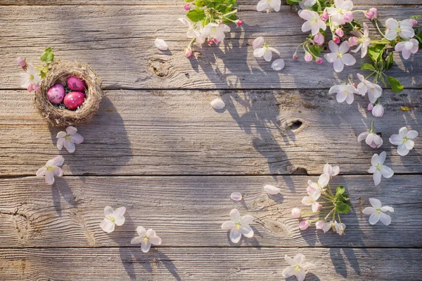 Uova di Pasqua in nido con fiori primaverili su sfondo vecchio di legno — Foto Stock