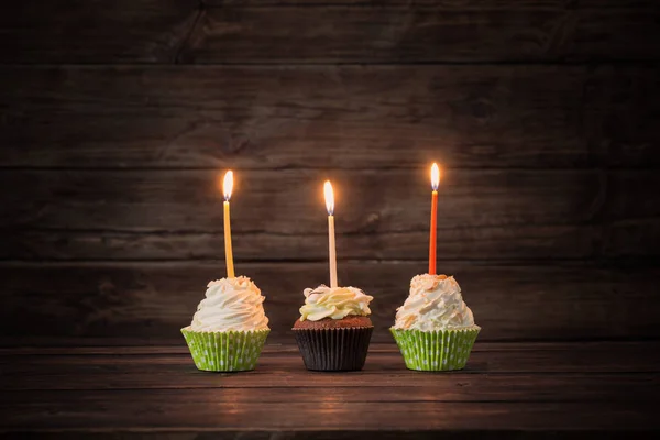 오래 된 어두운 나무 배경에 촛불 컵 케이크 생일 — 스톡 사진