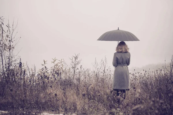 Junges Mädchen mit Regenschirm im Herbstfeld — Stockfoto