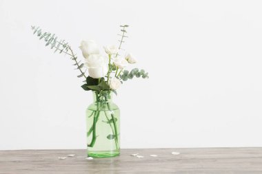 Okaliptüs twigs ve beyaz arka plan üzerinde cam vazoda gül