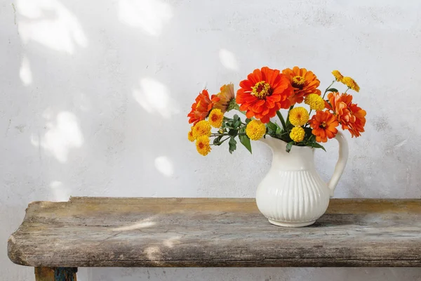 Herfst bloemen in werper op houten bankje — Stockfoto