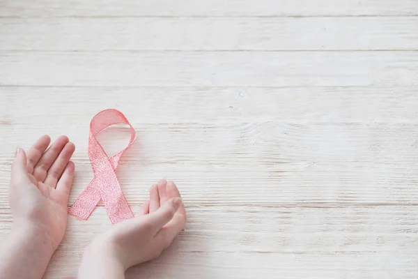 Cinta rosa en la mano como símbolo de la lucha contra el cáncer de mama — Foto de Stock