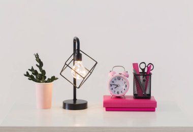 Beyaz arka plan üstünde defter ile pembe çalar saat