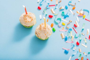 konfeti ve cupcake mavi kağıt arka plan üzerinde doğum günü şapkası