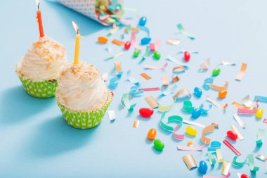 konfeti ve cupcake mavi kağıt arka plan üzerinde doğum günü şapkası