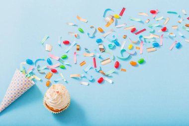 konfeti ve cupcake mavi kağıt arka plan üzerinde doğum günü şapkası