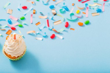 konfeti ve cupcake mavi kağıt arka plan üzerinde doğum günü şapkası