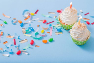 konfeti ve cupcake mavi kağıt arka plan üzerinde doğum günü şapkası