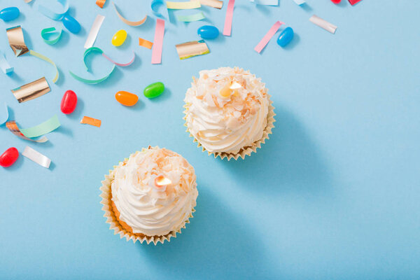 birthday hat with confetti and cupcake on blue paper background