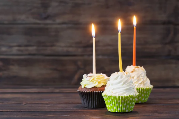 Cupcakes de aniversário com velas no fundo de madeira escuro velho — Fotografia de Stock