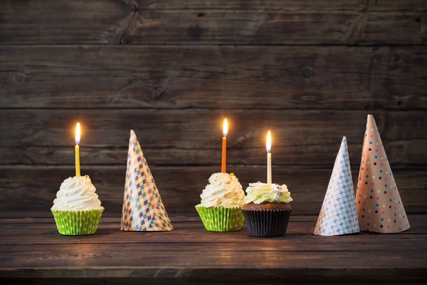 Urodziny cupcakes ze świecami na stary ciemne podłoże drewniane — Zdjęcie stockowe