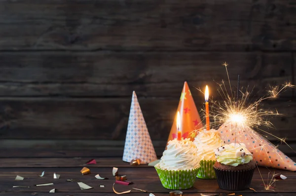 Cupcakes de aniversário com velas no fundo de madeira escuro velho — Fotografia de Stock