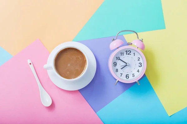 Kopje koffie en alarmklok op pastelpapier achtergrond — Stockfoto