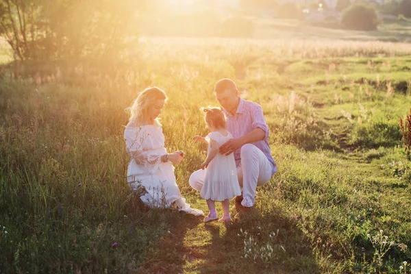 Gelukkige familie in zomer park bij zonsondergang — Stockfoto