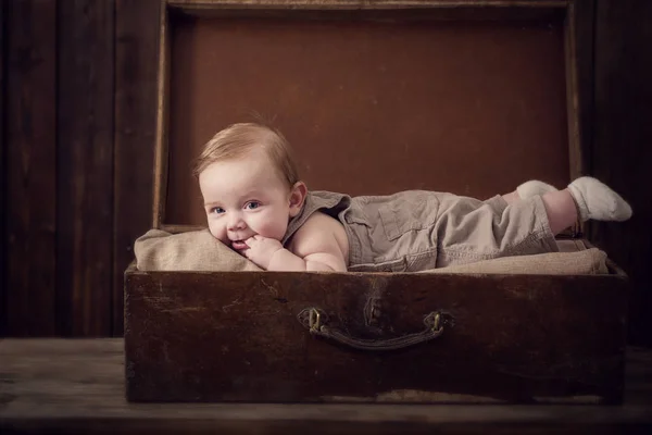 Petit bébé en valise sur fond bois — Photo