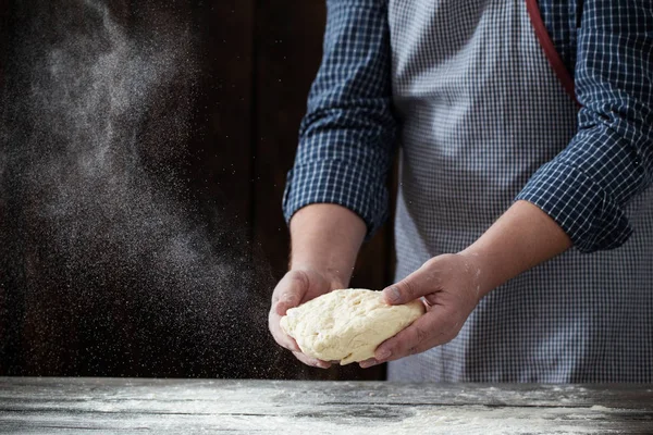 Mãos cozinhando massa no fundo de madeira escura — Fotografia de Stock