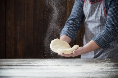  hands cooking dough on dark wooden background clipart