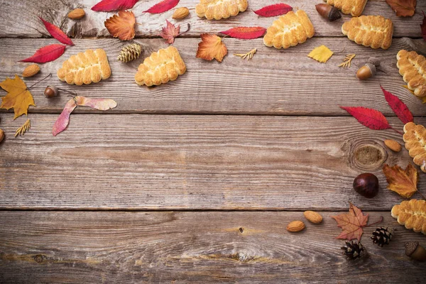 Cookies and autumn leaves on  wooden background — Stock Photo, Image
