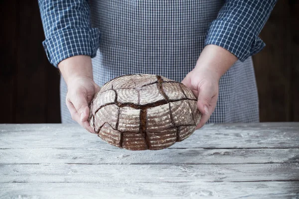 Händer med bröd på trä bakgrund — Stockfoto