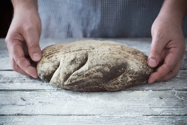 Τα χέρια με ψωμί σε φόντο ξύλινη — Φωτογραφία Αρχείου