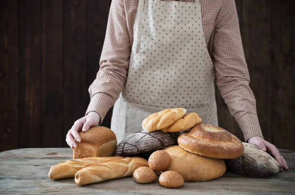 hand and different types of bread on wooden background