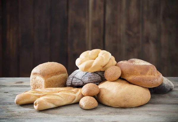 Different types of bread on wooden background — Stock Photo, Image