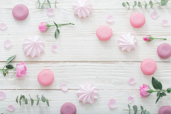 Weißer Holzhintergrund mit rosa Blüten, Makronen und Blättern — Stockfoto