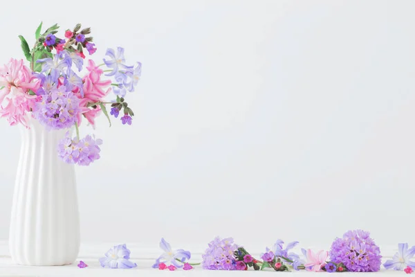 Flores azules y rosadas en jarrón sobre mesa blanca —  Fotos de Stock