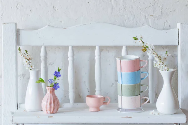 Чашки і вази з весняними квітами на старовинній дерев'яній білій полиці — стокове фото