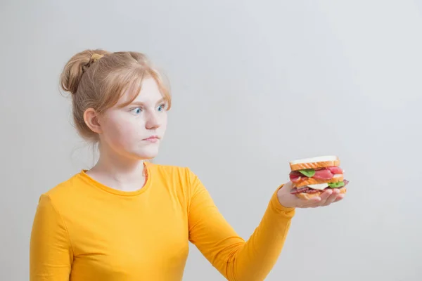회색 배경에 샌드위치와 십 대 소녀 — 스톡 사진