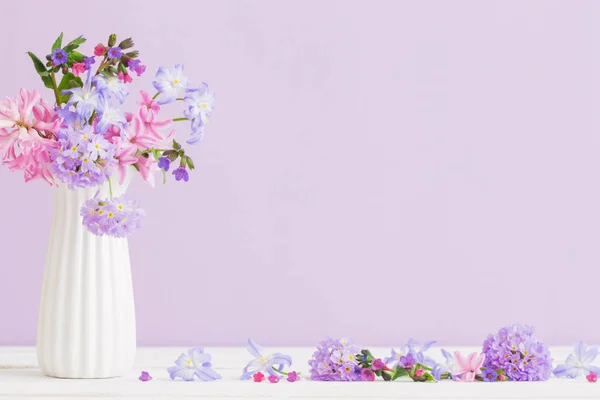 blue and pink flowers in vase on white table