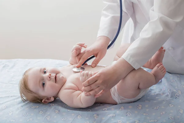 Médico escuta criança pequena com estetoscópio — Fotografia de Stock