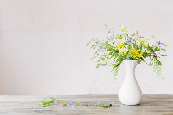 Flores silvestres en jarrón blanco sobre fondo pared vieja — Foto de Stock
