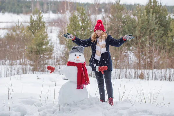 Menina adolescente feliz com boneco de neve na floresta de inverno — Fotografia de Stock