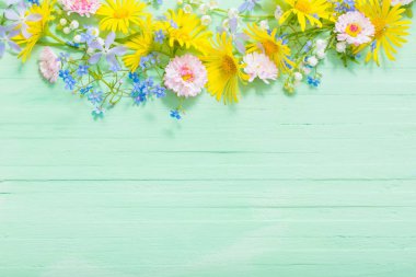 frame of beautiful flowers on green wooden background clipart
