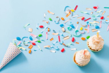 konfeti ve cupcake mavi kağıt arka plan üzerinde doğum günü şapkası