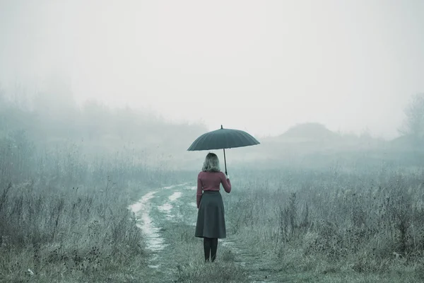 Giovane ragazza con ombrello in campo autunnale — Foto Stock