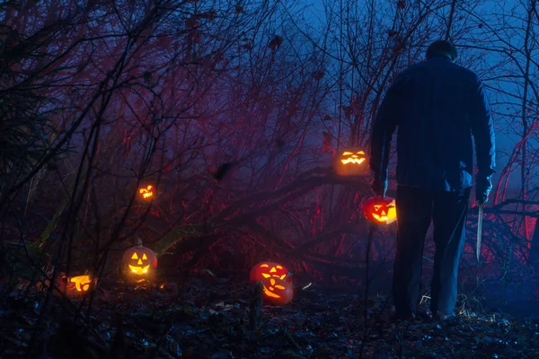 Homme effrayant dans la forêt de nuit coupe citrouilles Halloween — Photo