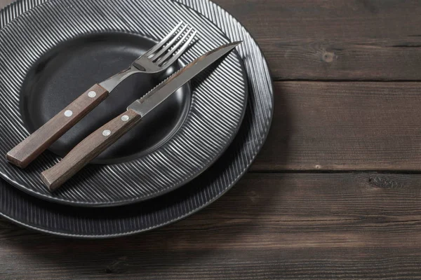 Black plates on wooden background — Stock Photo, Image