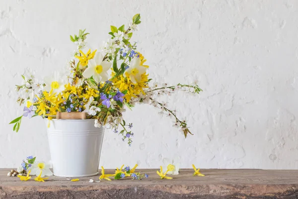 Lente bloemen in witte emmer op oude houten tafel — Stockfoto