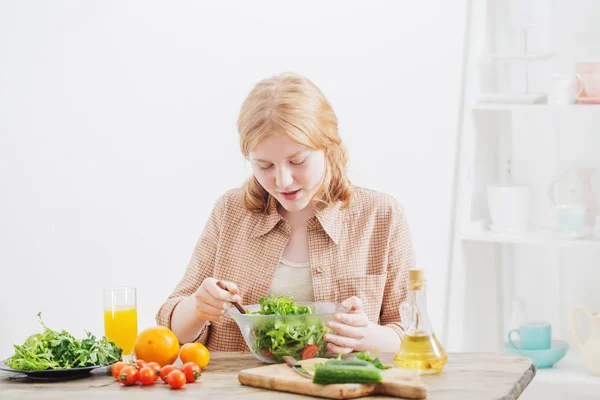 Tonåring flicka äter sallad hemma — Stockfoto