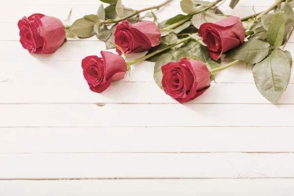 Rosas vermelhas sobre fundo de madeira branco — Fotografia de Stock