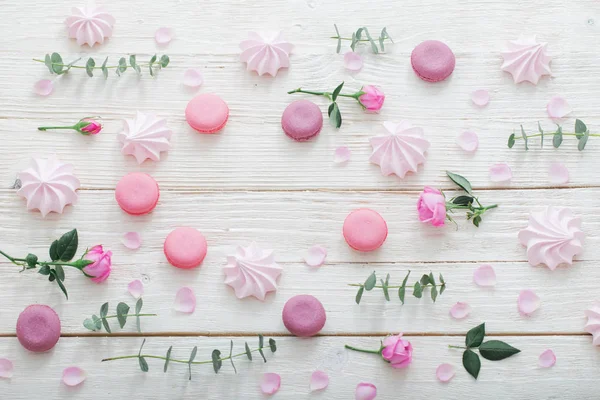 Fondo bianco in legno con fiori rosa, amaretti e foglie — Foto Stock